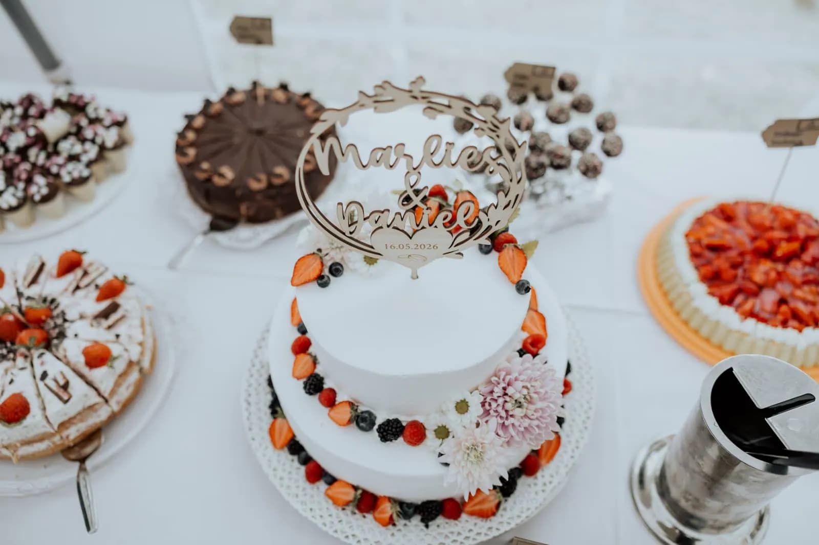 Hochzeitstorte von oben, daneben Obstkuchen und Pralinen am Buffet
