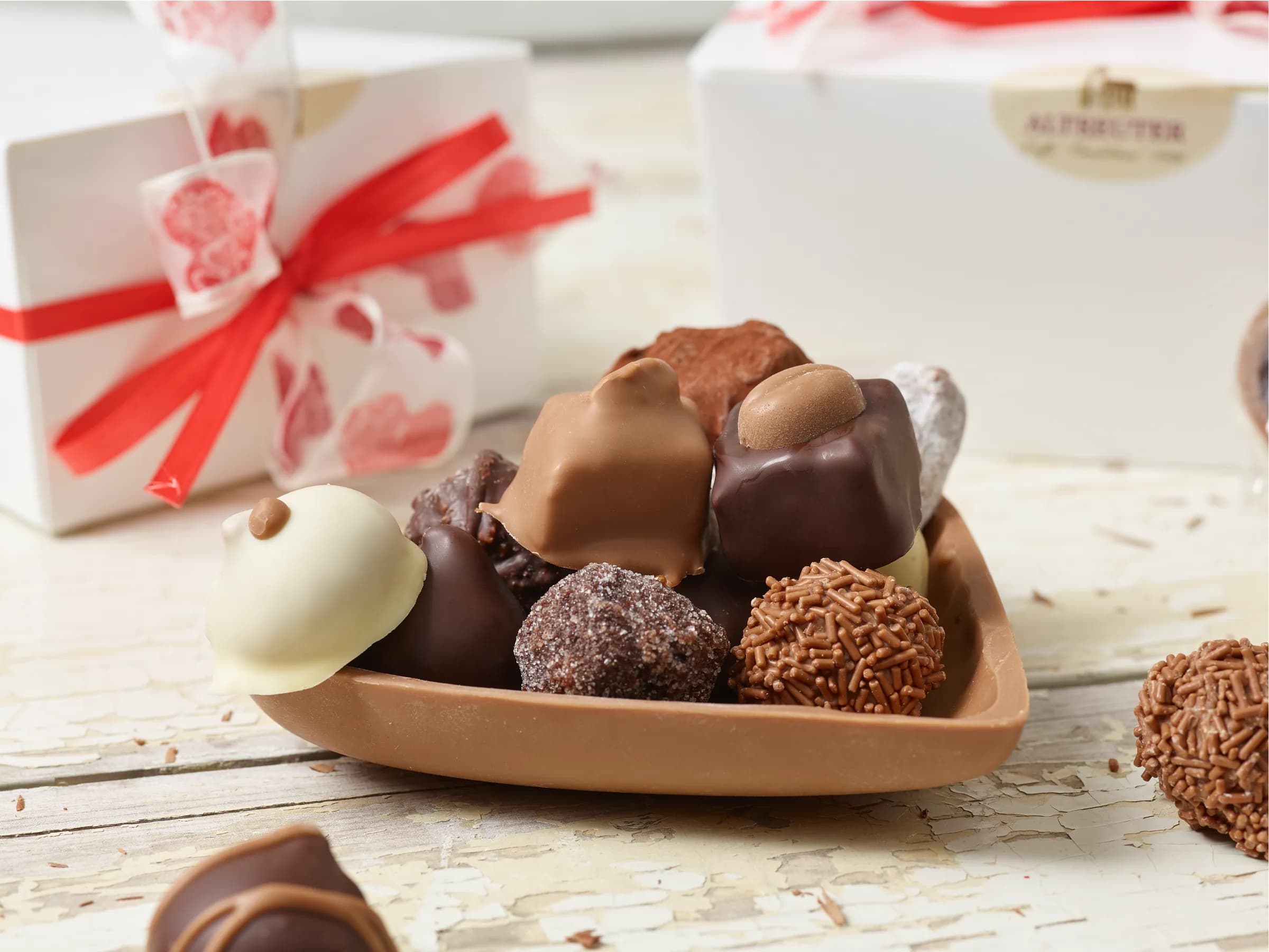 Herzförmige Schokoladenschale mit Pralinen vor der Altreuter-Schachtel