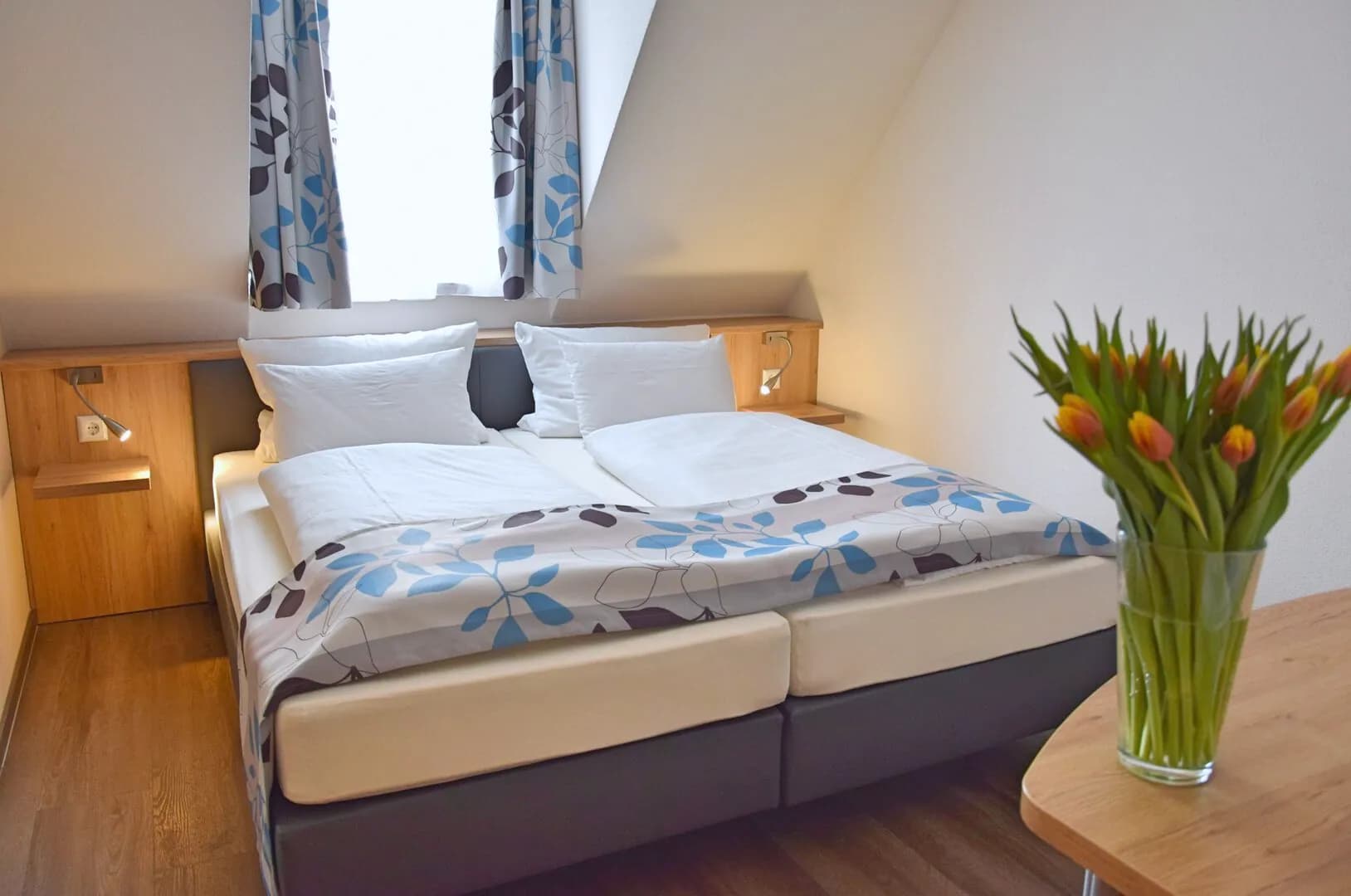 Doppelzimmer Kompakt: Doppelbett und Tulpen auf dem Tisch
